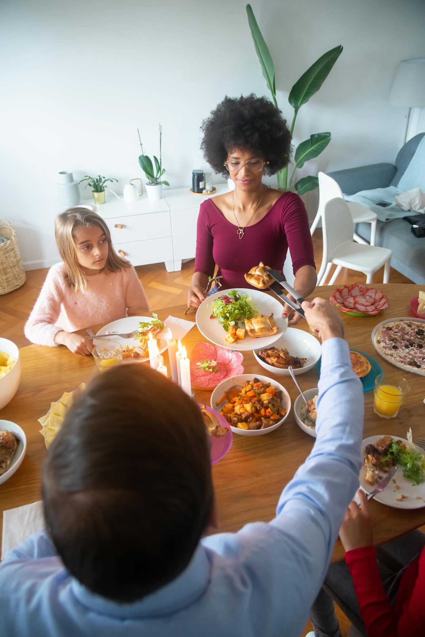 A warm family dinner scene with candles and diverse members sharing a meal indoors.